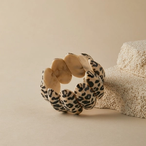 Detail showing elastic leopard print resin bracelet on stone texture background