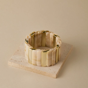 Détail d'un bracelet élastique large avec résine marbrée et accents métalliques dorés
