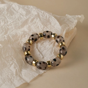 Leopard print acrylic beaded bracelet with gold metal spacers on minimalist background