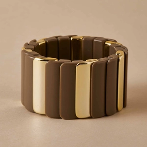 Détail des blocs de métal doré poli et mat marron sur un bracelet élastique moderne