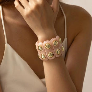 Vue macro d'un large bracelet en résine marbrée rose avec clous dorés pour femmes