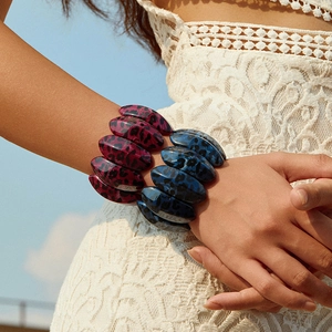 Wide leopard print acrylic stretch bracelets in purple and blue worn by a model