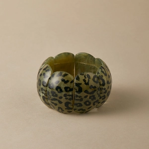 Macro view of leopard print wide resin bangle with polished multi-segment curved panels