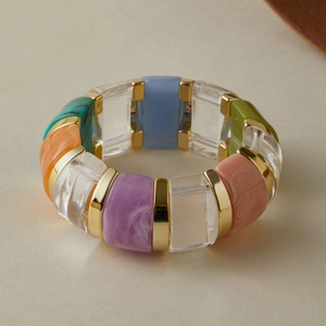 Detail of colorful acrylic beaded elastic bracelet with marble texture and gold accents