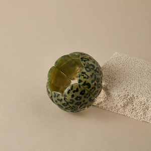 Detail of wide leopard print bangle featuring segmented acetate links and olive green tones