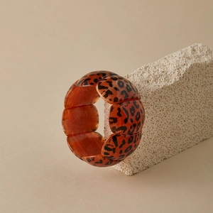 Detailed view of irregular leopard print wide resin bangle with amber translucent finish
