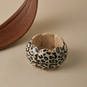 Detail of leopard print resin petal bracelet with elastic cord on beige background