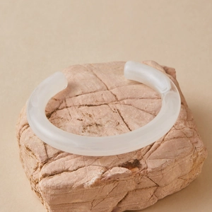 Detailed view of matte translucent resin open bangle on a natural stone base