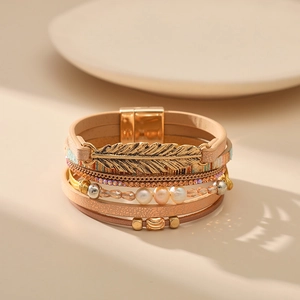 Détail d'un bracelet de style bohème multicouche en cuir avec plume dorée et fermoir magnétique