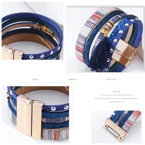Détail d'un bracelet bohème multicouche en cuir avec fermoir magnétique et pompon bleu