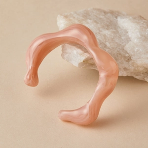 Vue détaillée du bracelet jonc rose en résine avec texture marbrée sur roche blanche