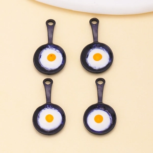 Detailed view of four fried egg skillet charms with black finish and yellow yolks