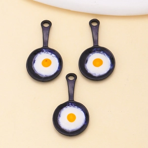 Close-up of three mini frying egg charms made of alloy for DIY jewelry and keychains