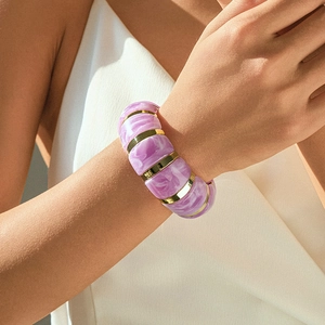 Detail of purple marble acrylic cuff bracelet with gold spacers on a model's wrist