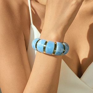 Close-up of bohemian blue marble resin bracelet with gold rings on a female model