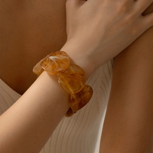 Dettaglio del bracciale a catena in resina ambrata con texture marmorizzata sul polso