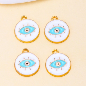 Close-up of four golden Evil Eye enamel charms for DIY jewelry making and necklace crafts