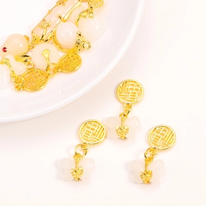 Golden Chinese Fu character pendant with white jade butterfly bead on white ceramic tray