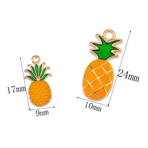 Macro view of pineapple enamel charms with gold trim showing sizes 17x9mm and 24x10mm