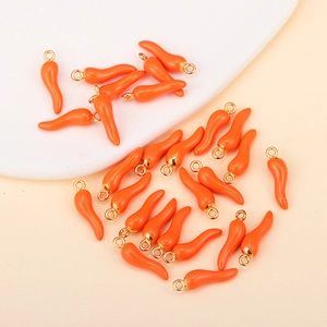 Macro shot of multiple orange chili pepper enamel pendants with gold hooks for DIY crafts