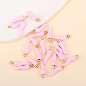 Flat lay view of pink chili pepper pendants with golden rings for DIY jewelry making