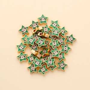Detailed macro of star-shaped evil eye beads with green enamel and gold alloy finish