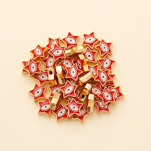 Macro detail of star shaped evil eye beads with red enamel and gold metal finish
