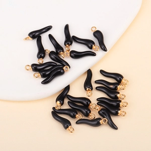 Macro detail of black chili pepper charms with gold rings for DIY jewelry making