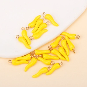 Macro shot of bright yellow chili pepper enamel charms with gold rings for DIY jewelry