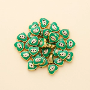 Close-up of heart-shaped evil eye charms with green enamel for DIY jewelry making