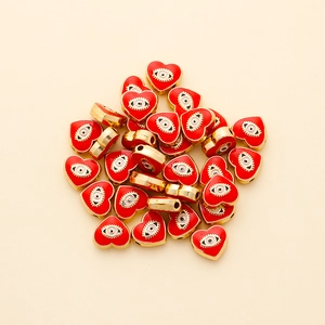 Detailed macro of heart-shaped evil eye beads with red enamel and gold plating