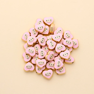 Macro view of heart-shaped pink enamel evil eye beads with gold-plated edges for DIY jewelry