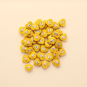 Macro detail of yellow heart-shaped evil eye enamel beads for DIY jewelry making