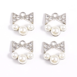 Vue détaillée de breloques nœud en argent avec perles blanches et strass étincelants