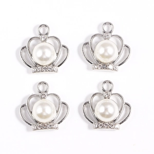 Vue détaillée des pendentifs couronne en argent avec perles blanches et strass