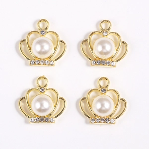 Détail de quatre pendentifs couronne dorés avec perles blanches et strass brillants
