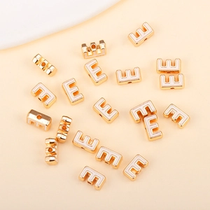 Détail de la perle lettre E en émail blanc doré avec trous latéraux pour bijoux DIY