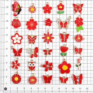 Detailansicht roter Emaille-Schmetterling- und Blumenanhänger auf einer Messskala