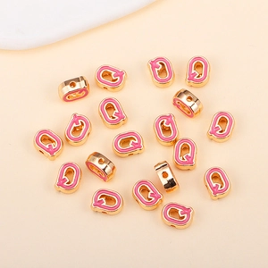 Détail macro d'une perle lettre Q en émail rose et doré pour bijoux DIY