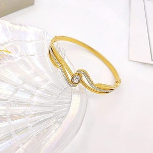 Eleganter goldener Edelstahlarmreif in Wellenform mit Zirkonia und großem Hauptstein