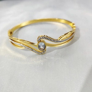 Makroaufnahme des 18K vergoldeten Wellenarmreifs mit großem ovalem Zirkon und Pavé-Diamanten