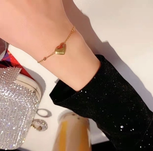Primo piano di una collana con ciondolo a cuore dorato minimalista con luce calda sul polso