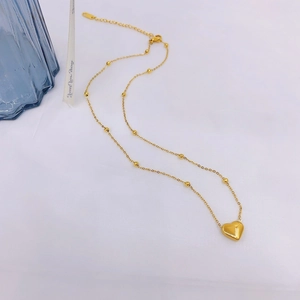 Dettaglio del ciondolo a cuore dorato su catena a sfere con maglie regolabili