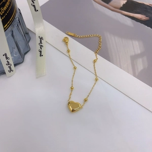 Elegant gold titanium heart bracelet featuring polished beads and adjustable lobster clasp