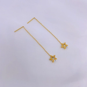Detailed macro view of gold-tone tassel ear threads with sparkling star pendants