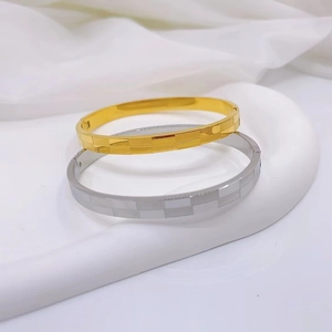 Detail of gold and silver checkerboard patterned stainless steel bangles with matte finish