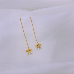 Detail of long gold star threader earrings with zircon inlay on a white silk fabric