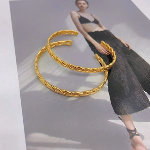 Detailansicht goldener gedrehter C-Form Armreifen mit klassischer Flechttextur auf Magazin