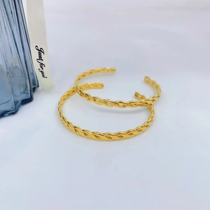 Detailansicht goldener gedrehter C-förmiger Armreifen mit hochglänzender Metallstruktur