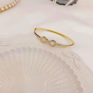Macro shot of 18K gold plated infinity bracelet with micro-pave white zircons on ceramic tray